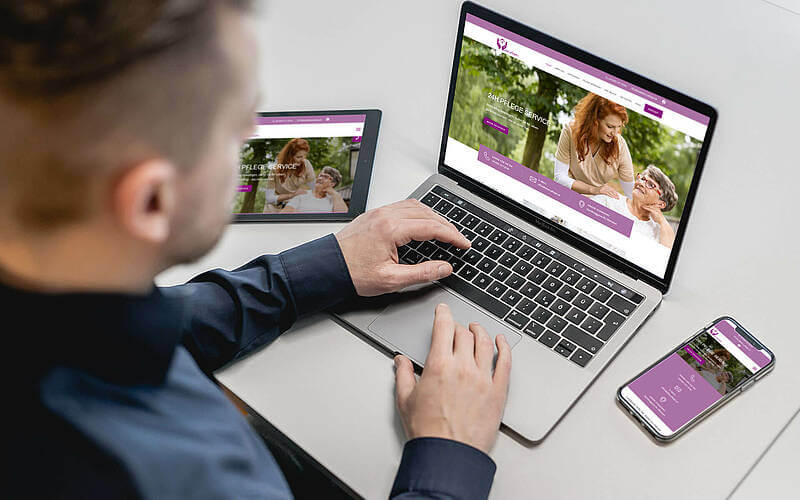 Mann betrachtet Website auf Laptop, Tablet und Smartphone für barrierefreien Zugang und responsives Design.