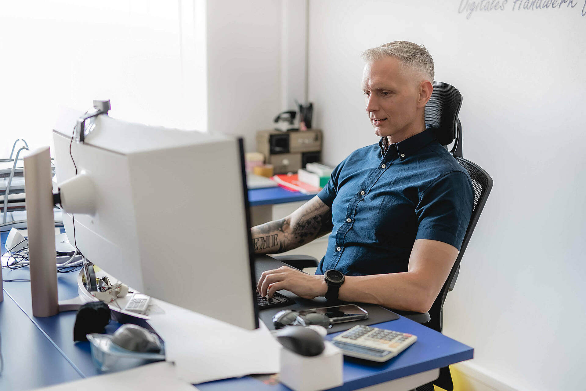 Mann am Computerarbeitsplatz im Büro, konzentriert am Bildschirm arbeitend.