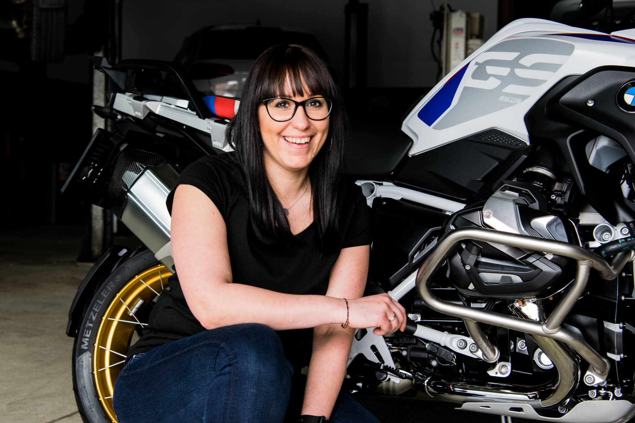 Frau lächelt neben einem Motorrad in der Werkstatt – moderne Technik und Begeisterung vereint.