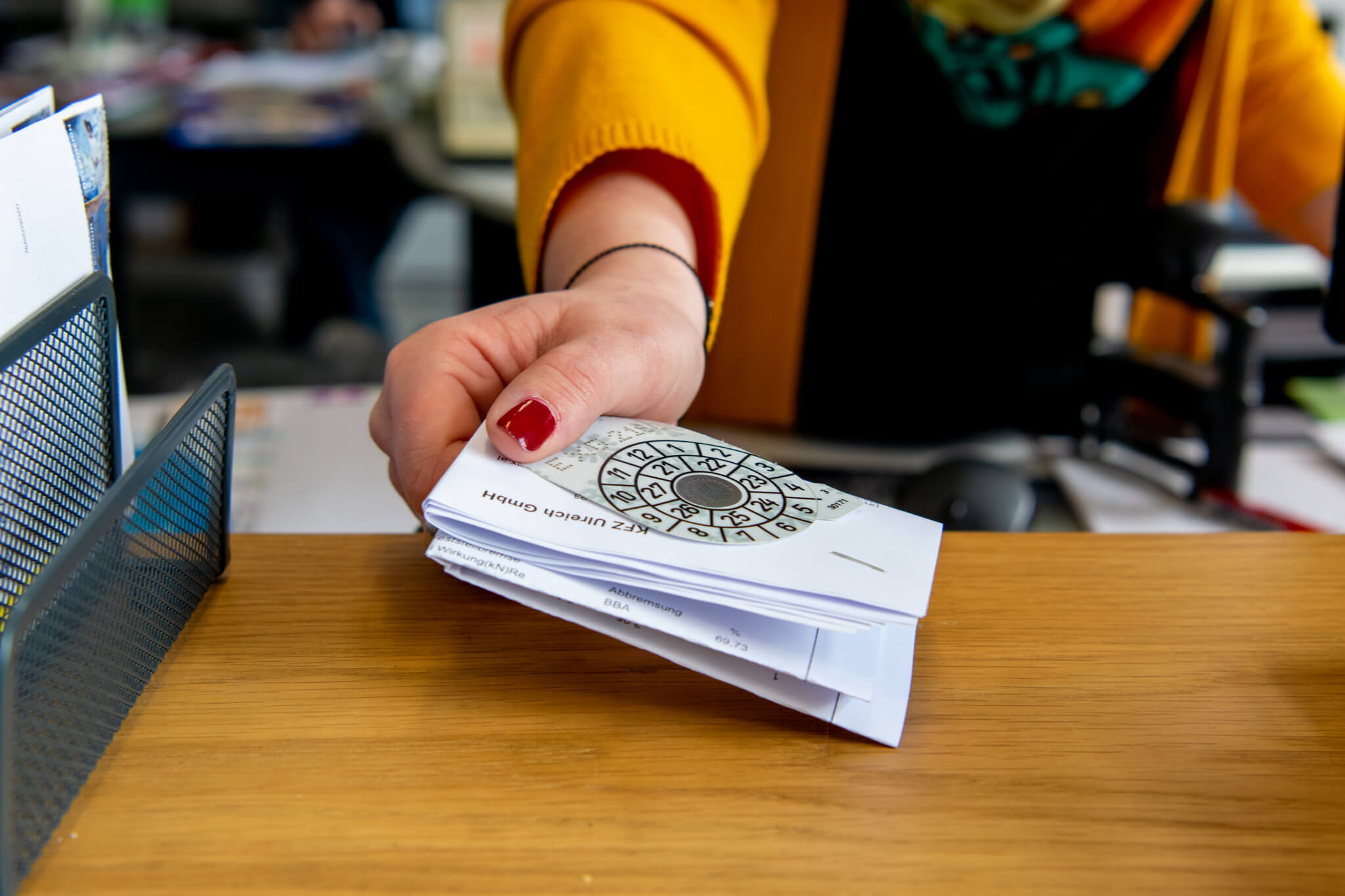 Mitarbeiterin reicht Dokumente mit Stempel über einen Schreibtisch, Nahaufnahme, Büroumgebung, Verwaltung.