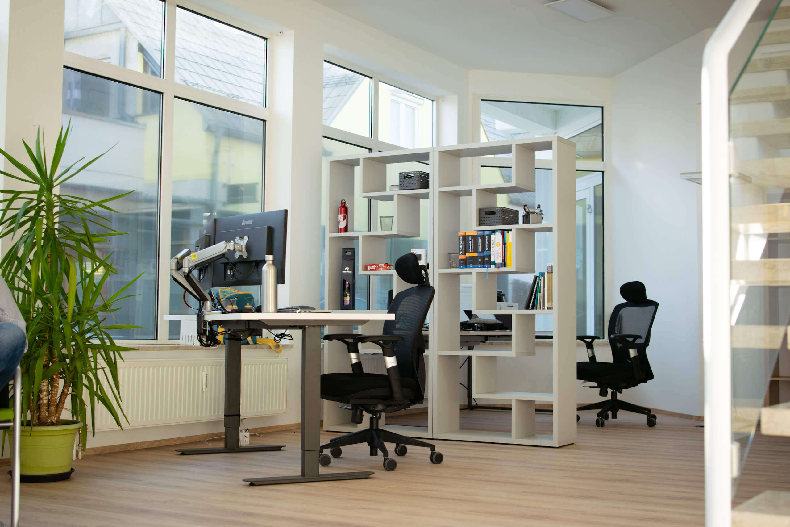 Modernes Büro mit ergonomischen Stühlen, großem Fenster und Pflanzen für eine inspirierende Arbeitsumgebung.