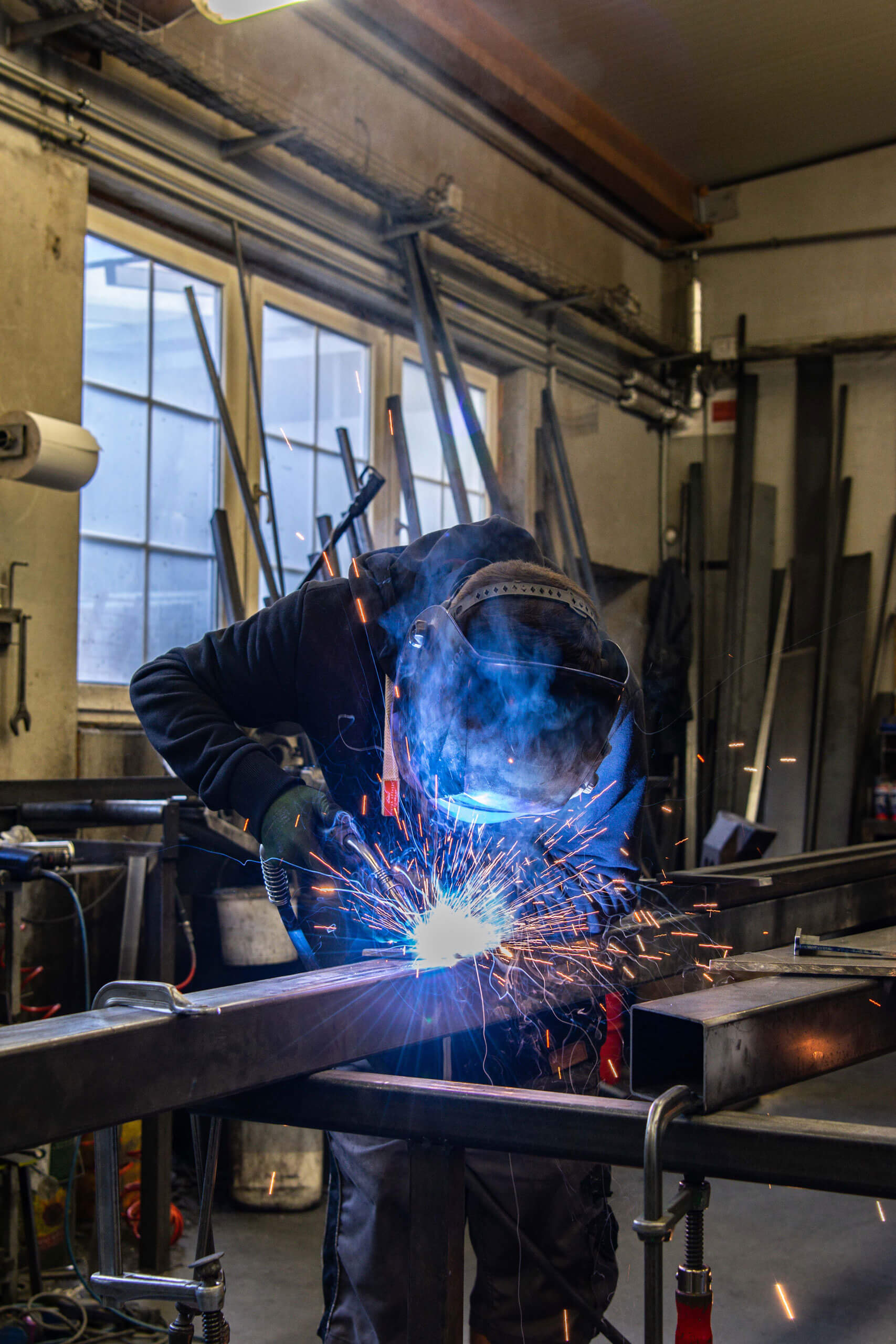 Schweißer bei der Arbeit in einer Werkstatt, Funken fliegen, Metall bearbeitend, industrielle Handwerkskunst.