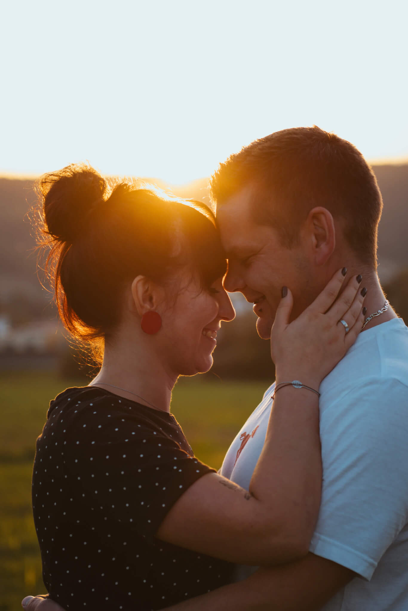 Paar im Sonnenuntergang, das sich liebevoll anschaut. Harmonie und Romantik in einer malerischen Landschaft.