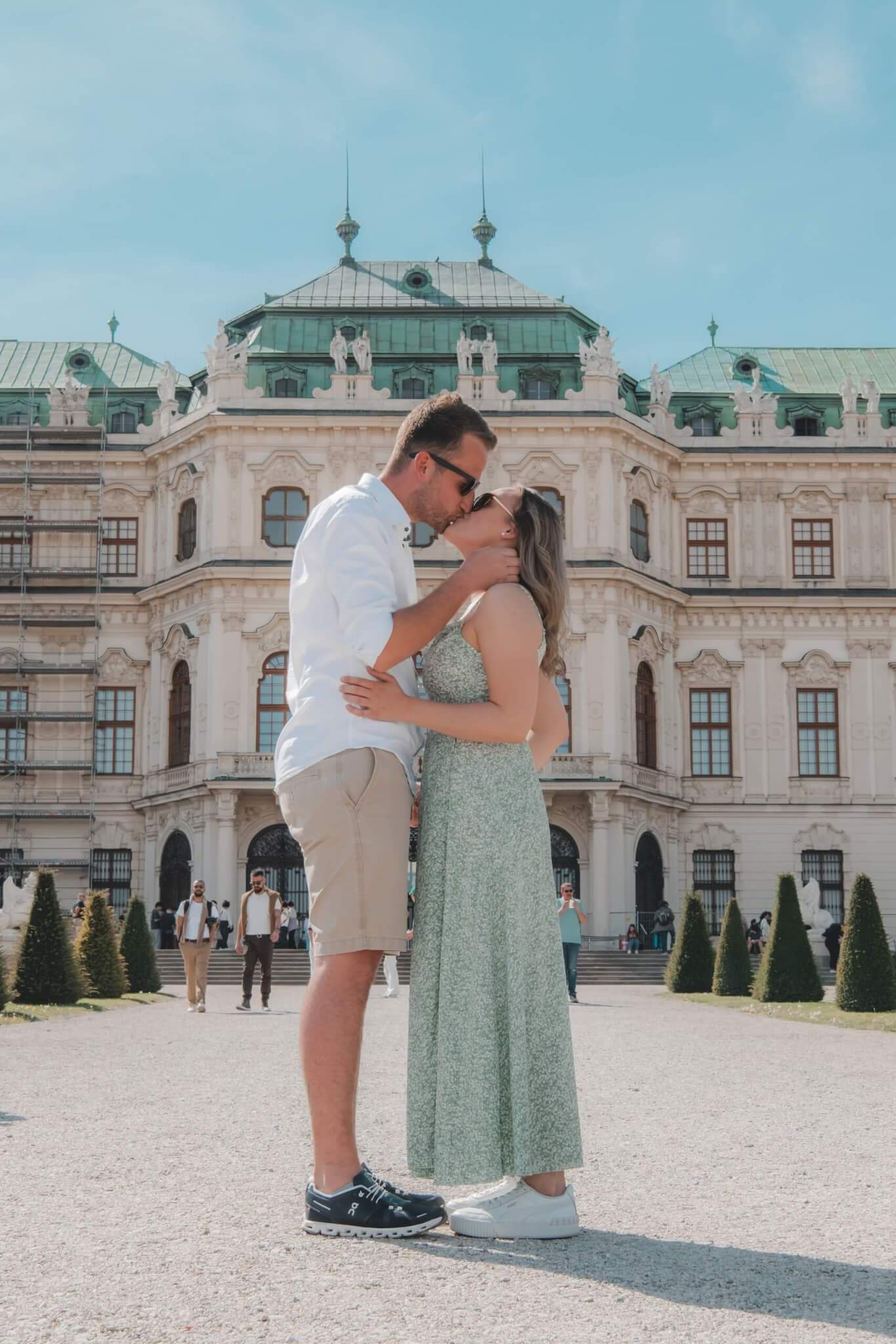 Pärchen küsst sich vor dem barocken Schloss Belvedere in Wien an einem sonnigen Tag.