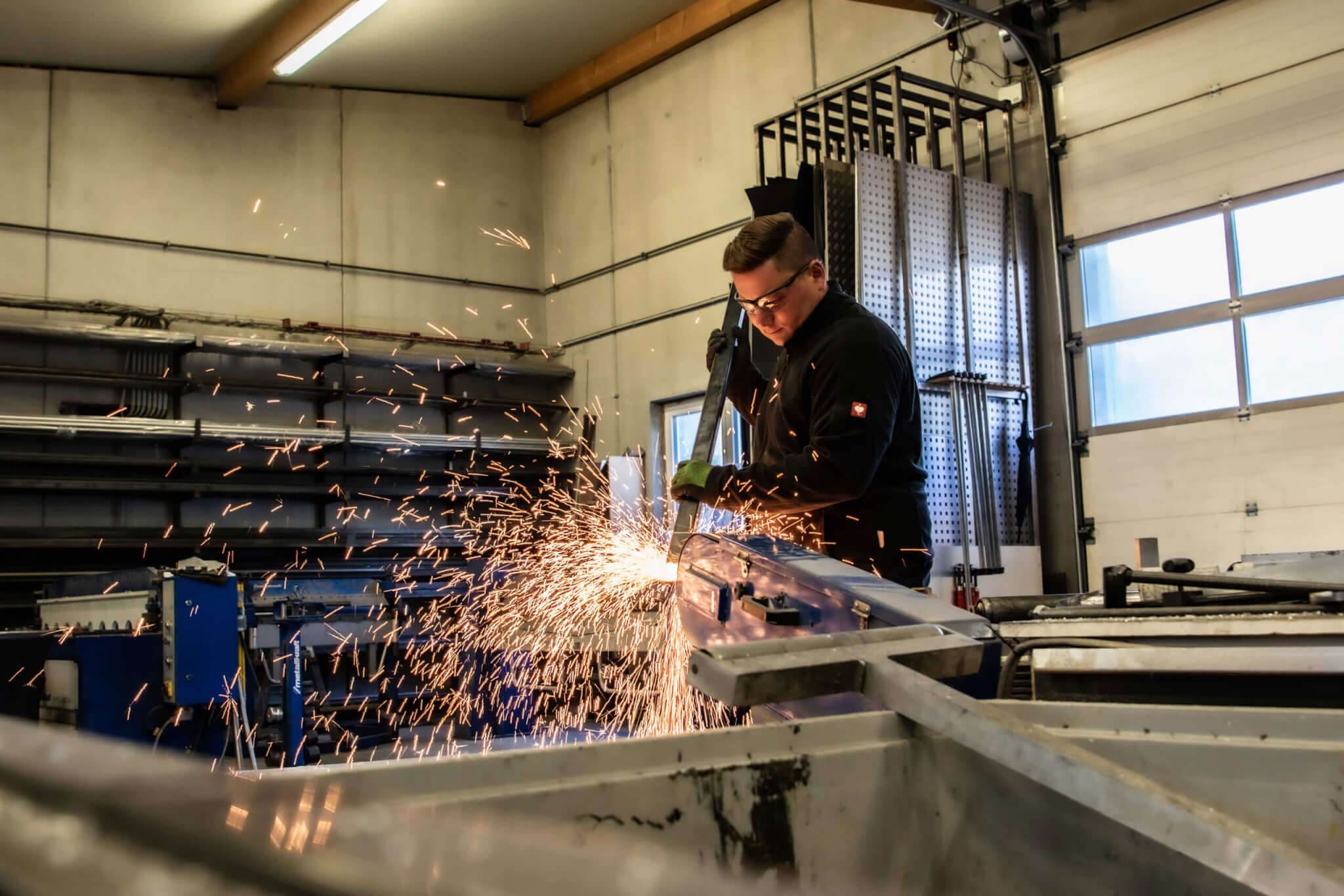 Metallarbeiter beim Schweißen in Werkstatt, Funken sprühen. Arbeitsplatzsicherheit, industrielles Handwerk.