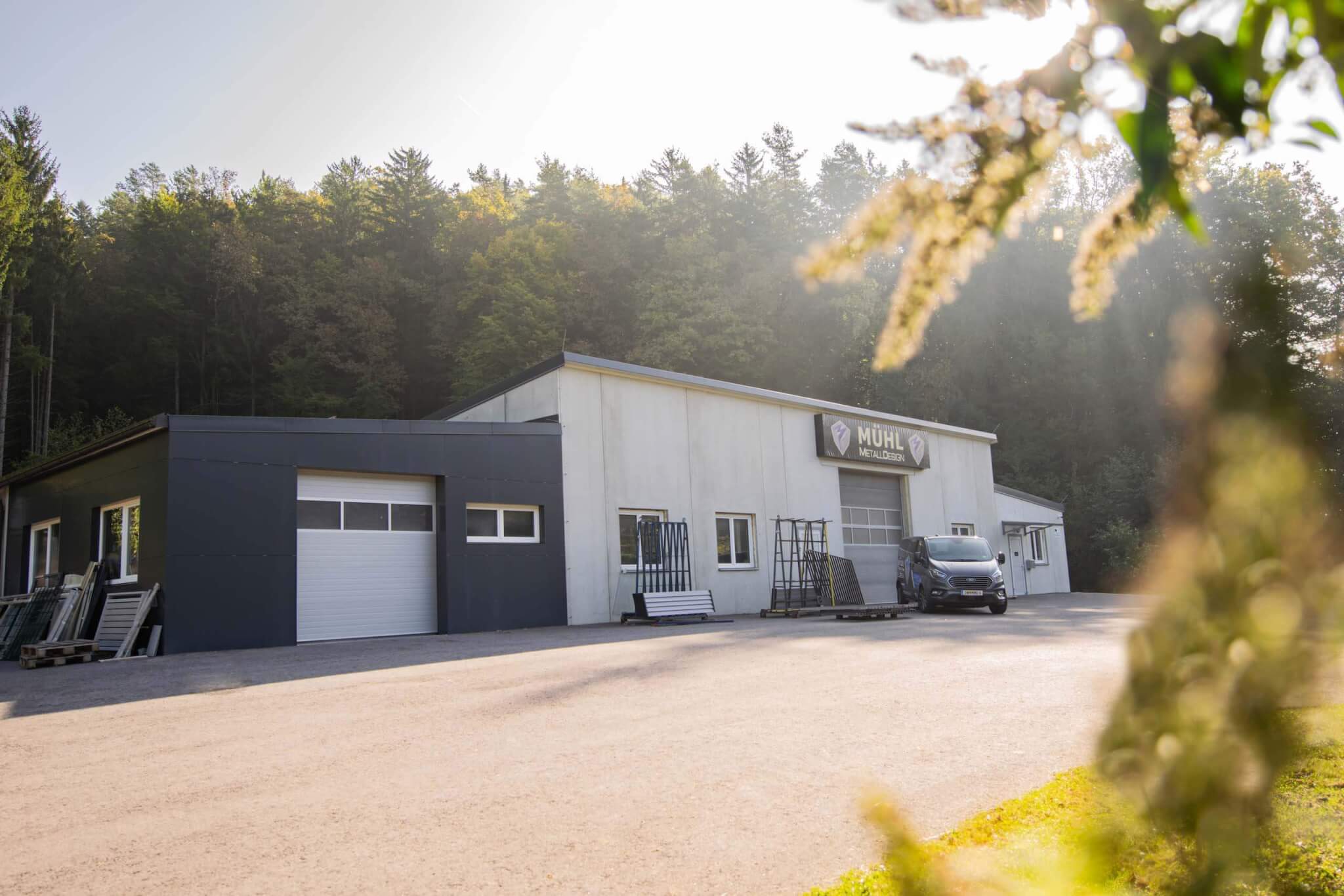 Industriegebäude im Grünen mit Firmenfahrzeug, Morgenlicht erhellt die Szene.